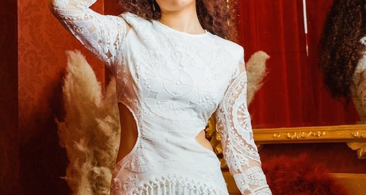 Naomicheyanne press photo wearing an elegant white dress.