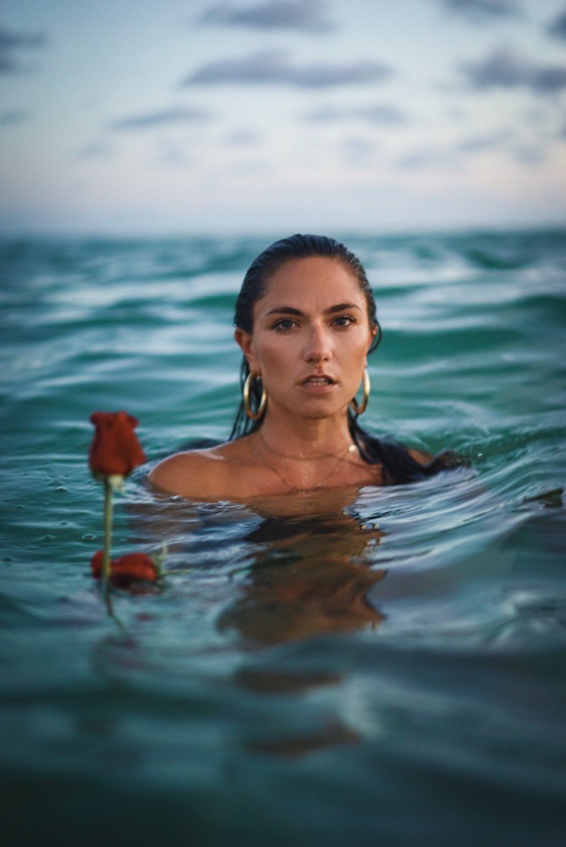 Camille Trust press photo swimming in the ocean beside a floating red rose
