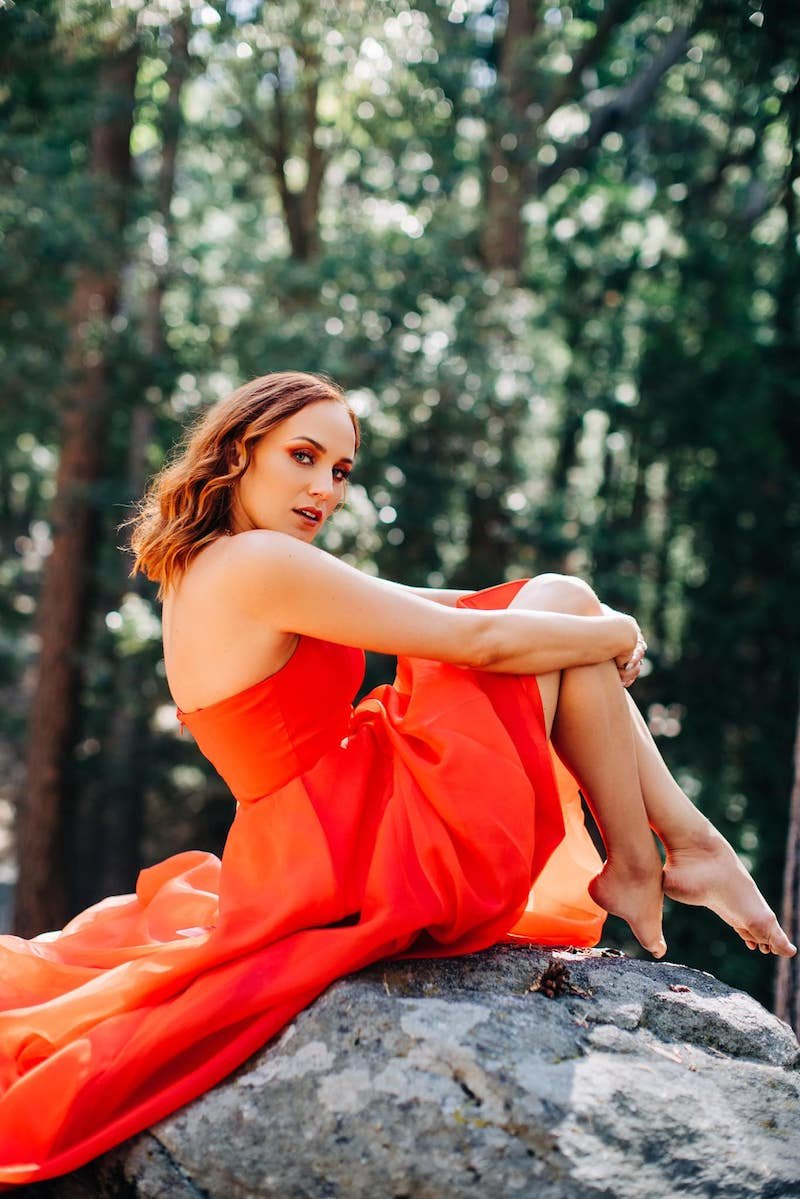 Kara Connolly press outside wearing a reddish-orange dress