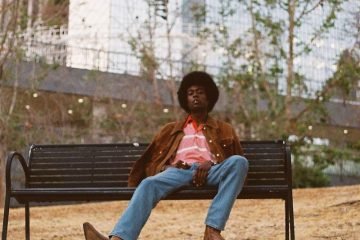 PawPaw Rod press photo outside wearing a brown jacket with matching cowboy boots