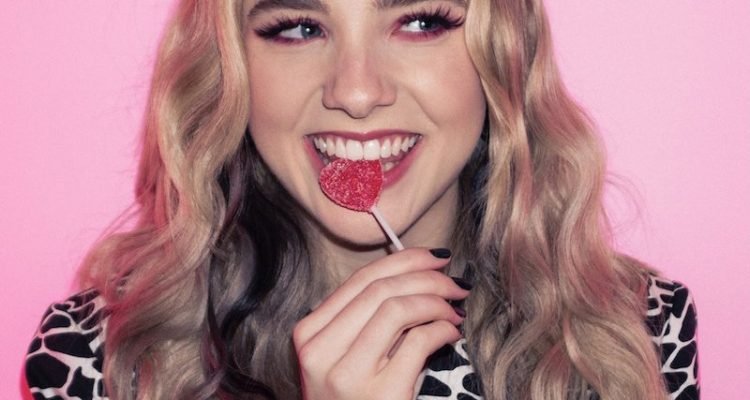 Rayne - “Sour Candy” press photo biting on a sour red lollipop