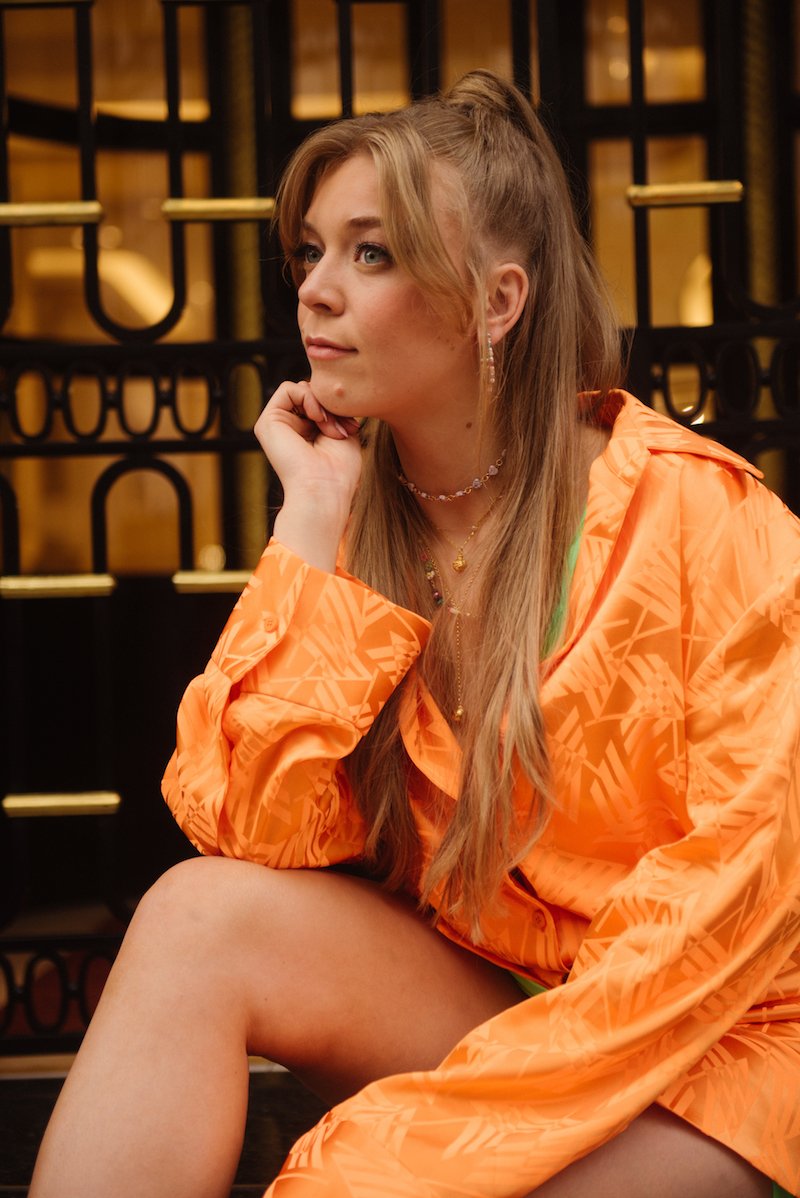 Becky Hill press photo wearing an orange and green outfit