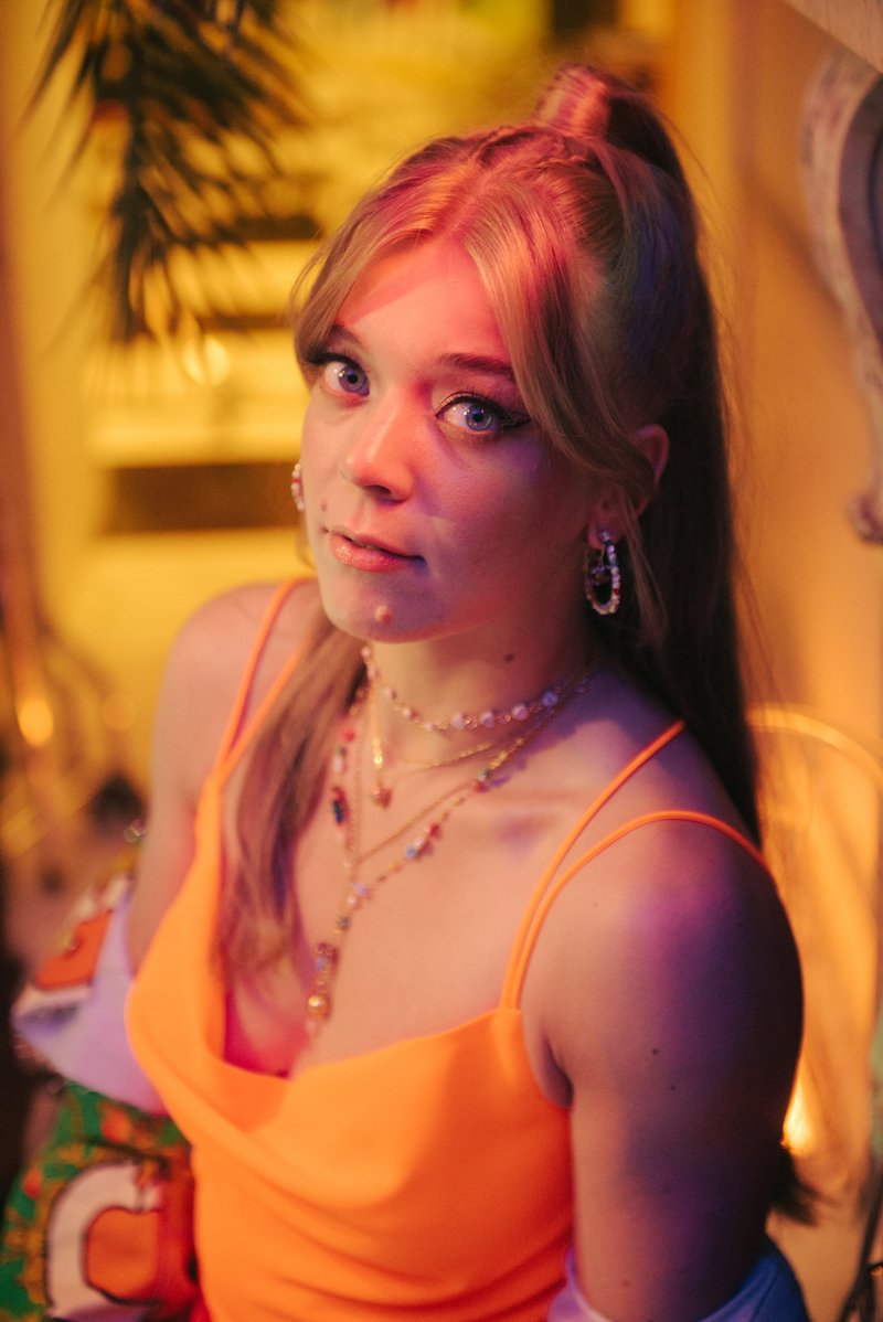 Becky Hill press photo wearing an orange and green outfit