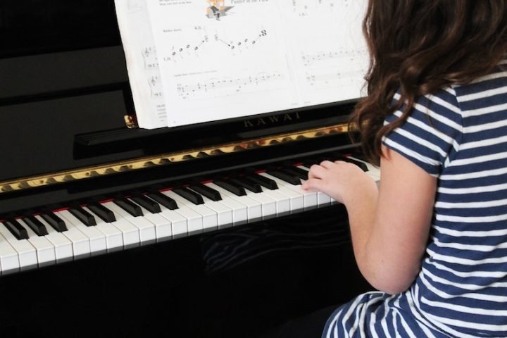 Young music girl playing a piano