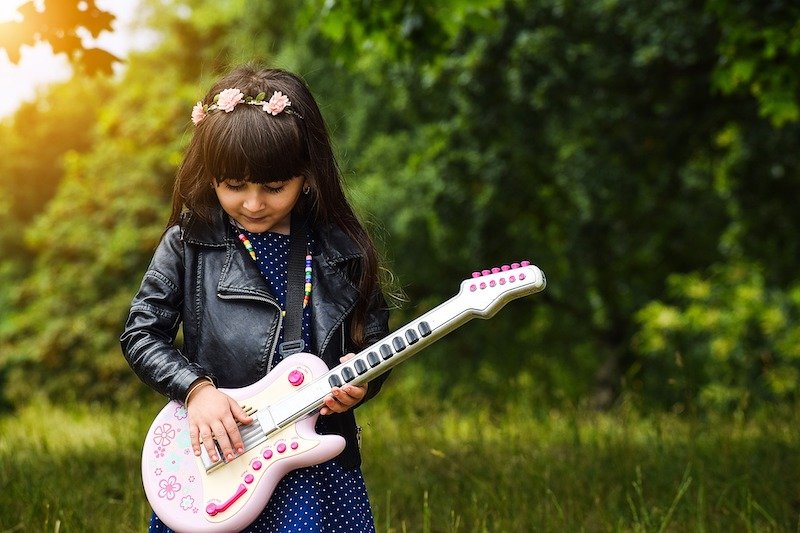 happy girl, kid musician with a toy electric guitar