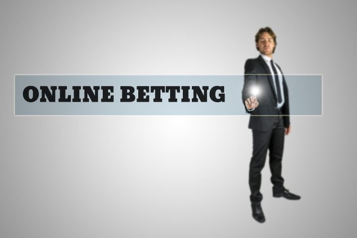 Young man in elegant suit activating Online betting button on virtual screen.